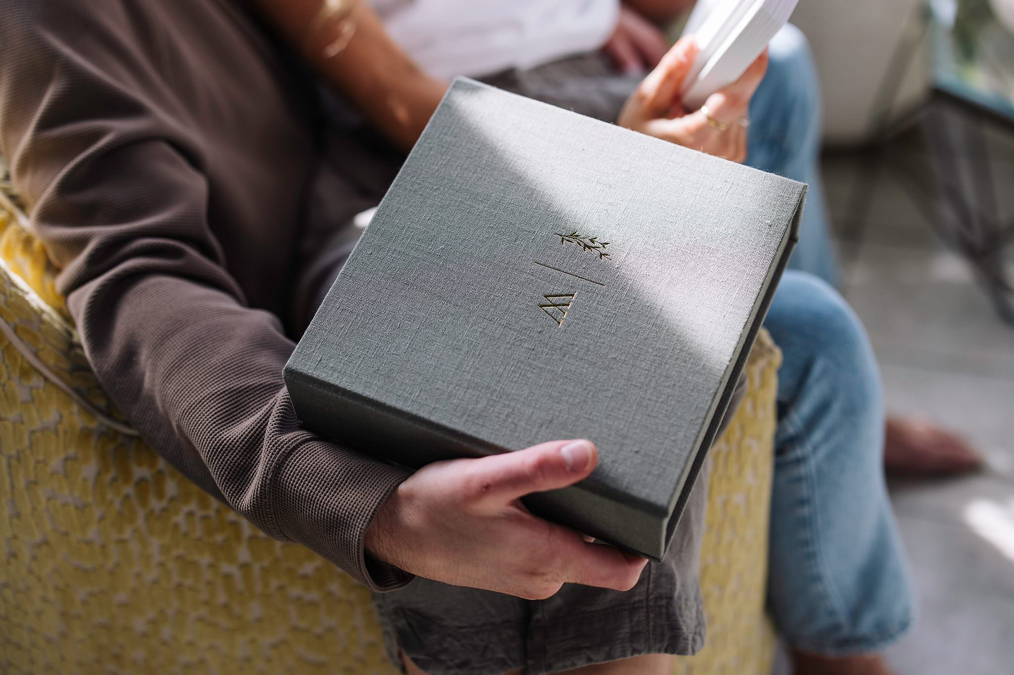 A debossed monogram on the lid of a grey fabric album box