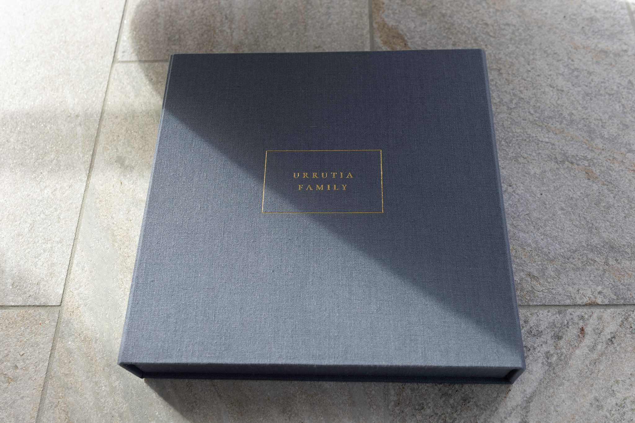 A personalized fabric album box on a sunlit stone floor