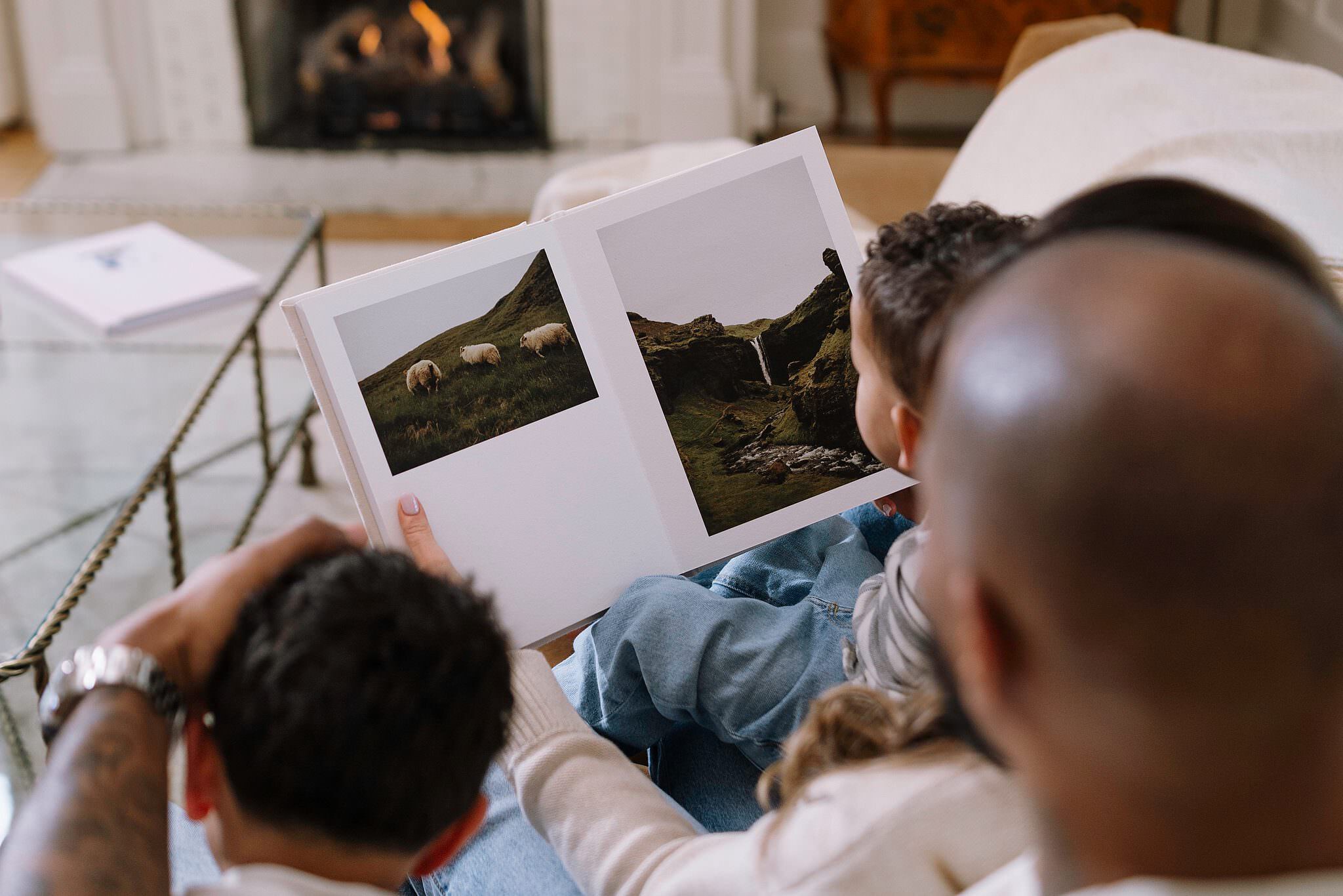 A family on the sofa together, leafing through an album spread in soft afternoon light