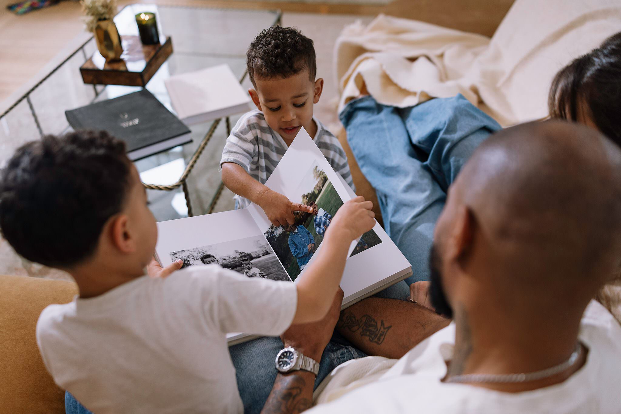 An album page lifted in both hands, a child reaching in to point at the layout