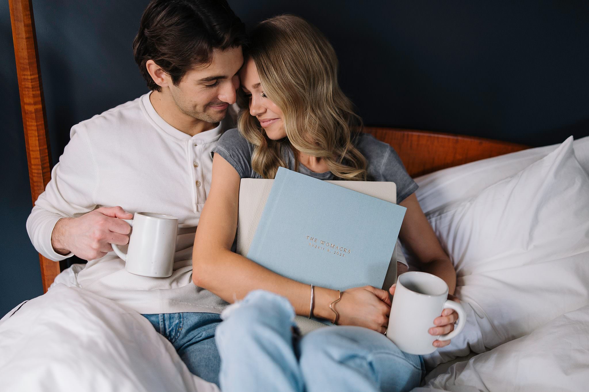 A couple in bed in the morning, mugs in hand, the blue album resting between them