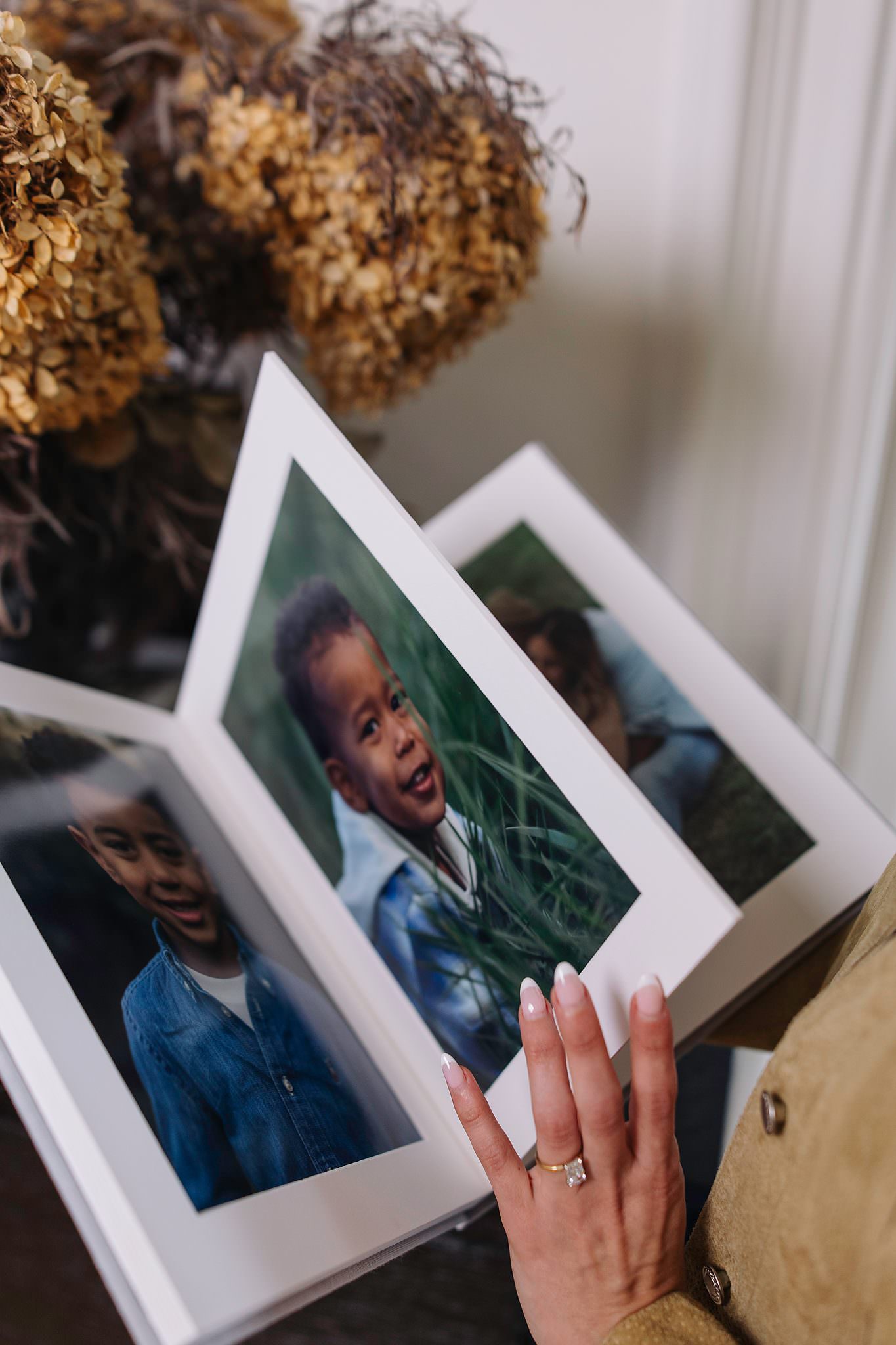 A matted folio album opened to a bright portrait of a laughing child, white mat and gold ring softly framing the page