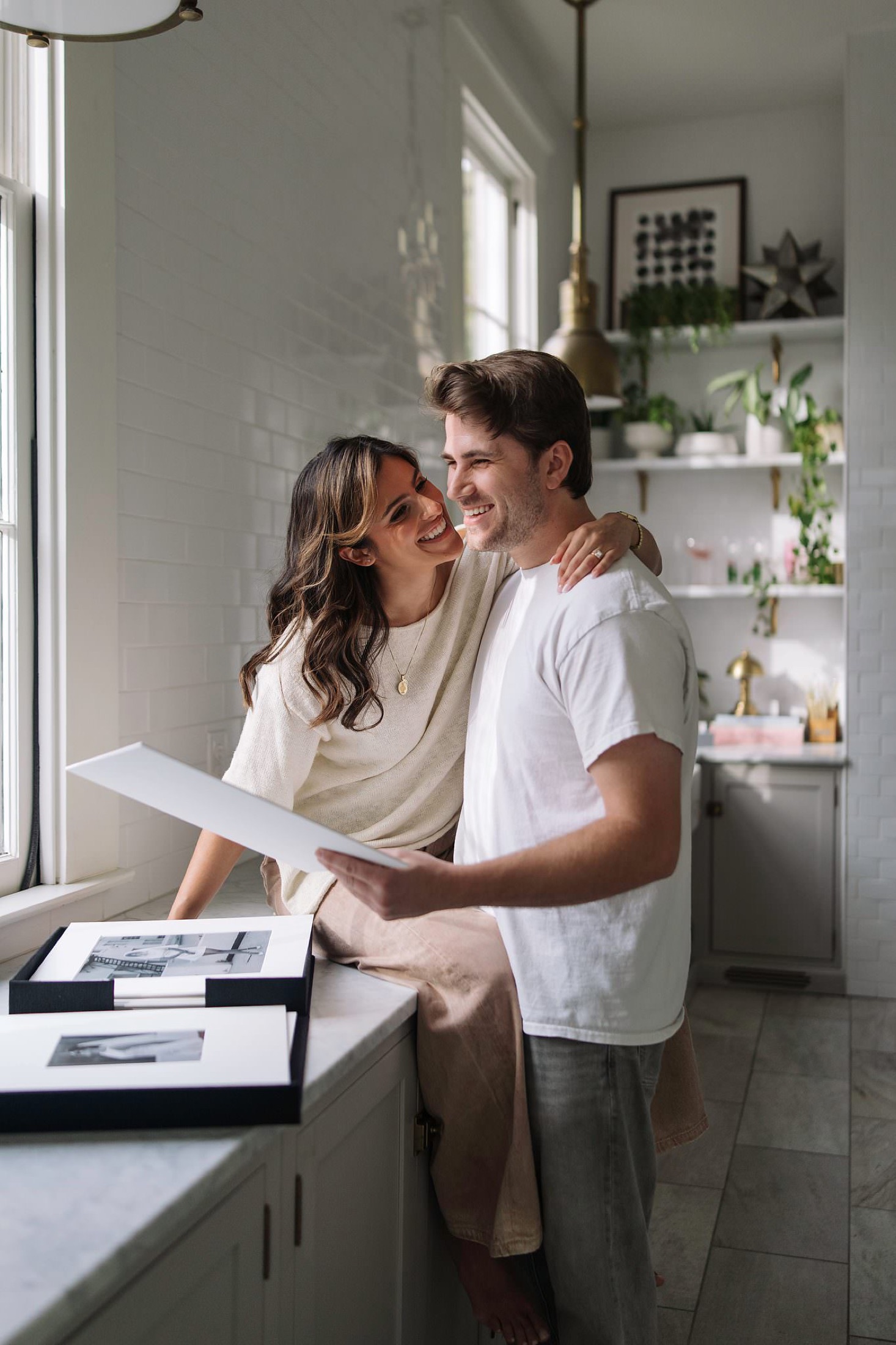 A couple sharing a matted print in a sunlit kitchen