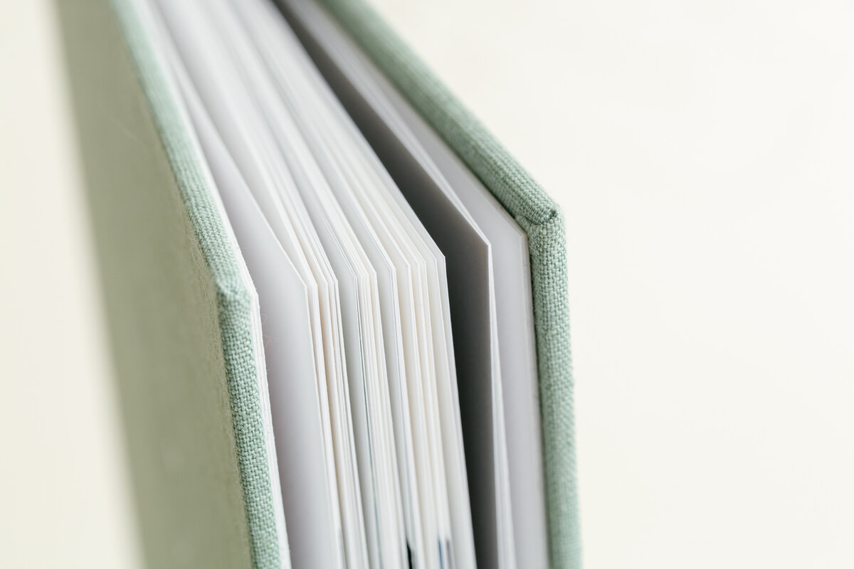 Hardcover photo book with sage linen spine and fanned pages