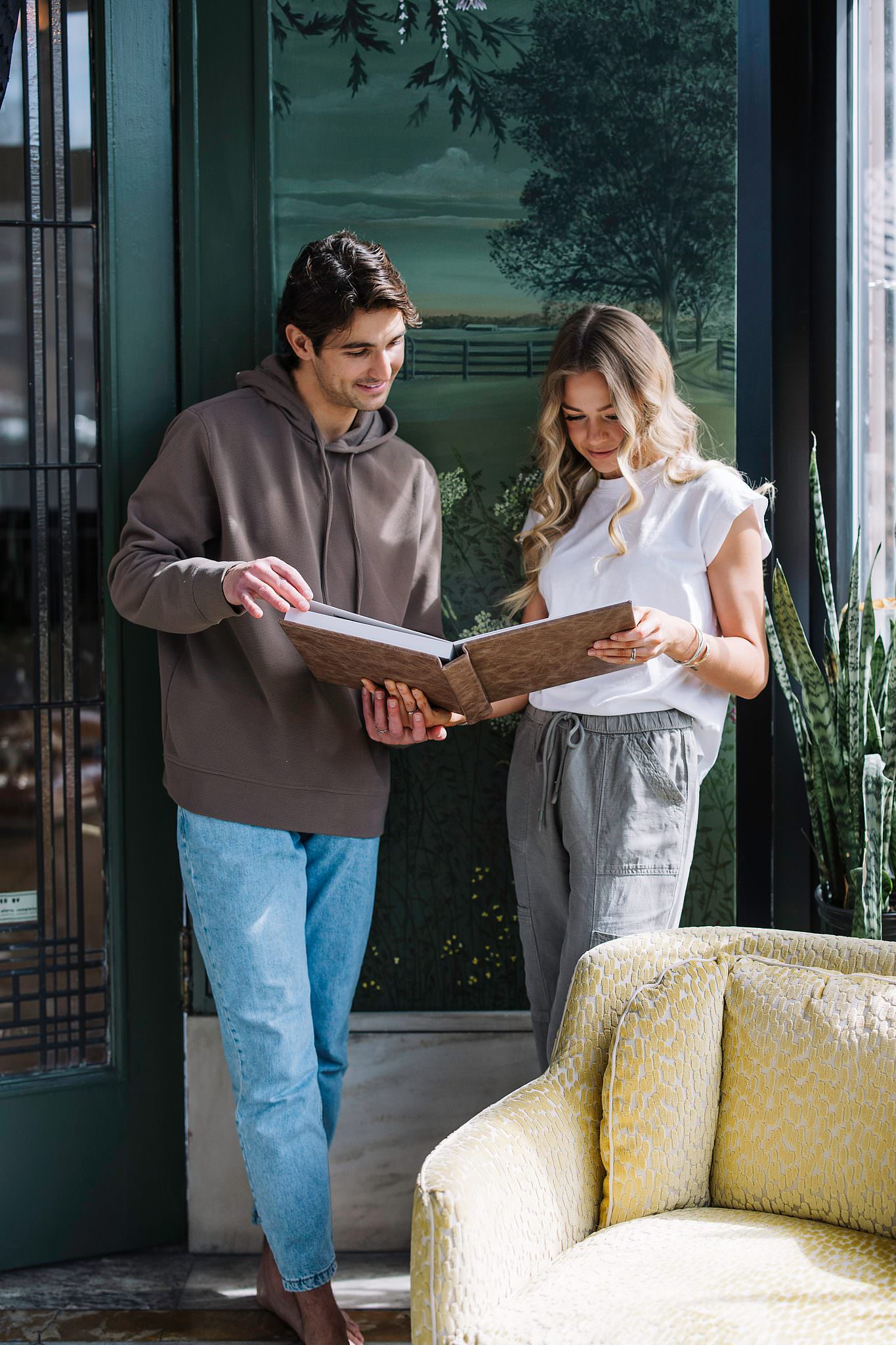 A couple standing together turning the pages of a debossed leather album